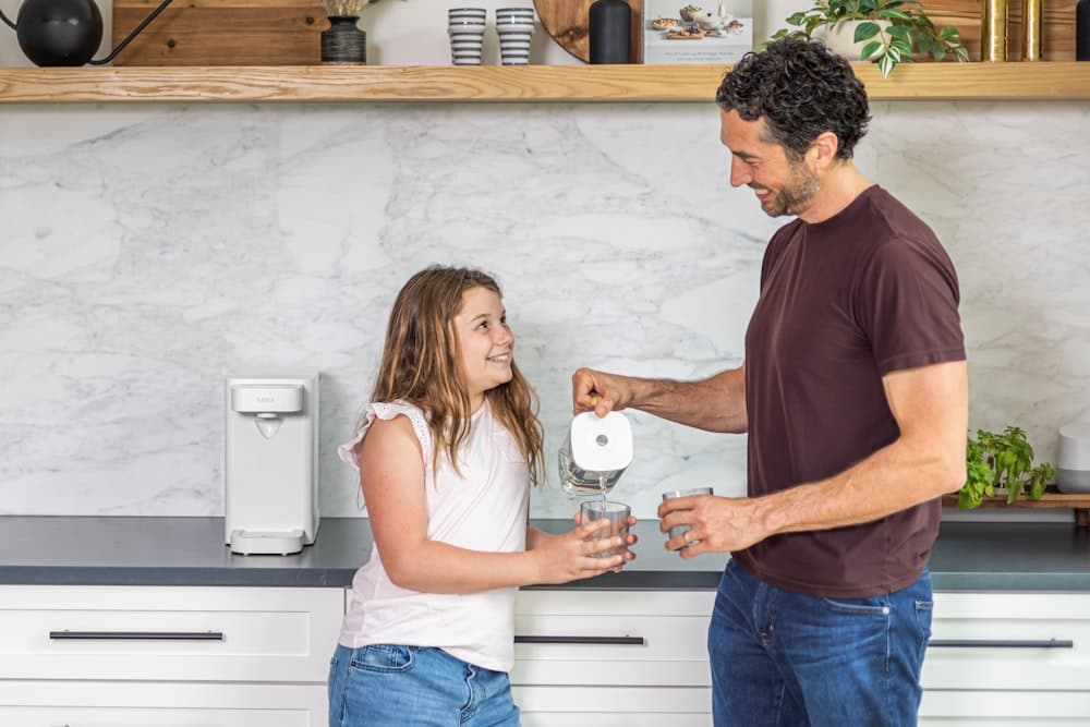 Family using Sans water purifier in modern kitchen